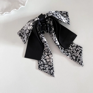 Elegant French bow hair claw clip with black satin and floral ribbon on a white surface