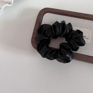 Elegant black pleated scrunchie with metallic leather luster for high-end hair styling