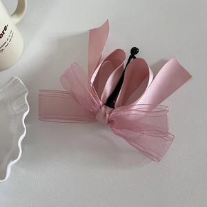 Détail d'un nœud papillon multicouche en tulle rose avec barrette banane élégante