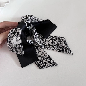 Detail of floral printed satin bow hair claw clip with long streamers in hand