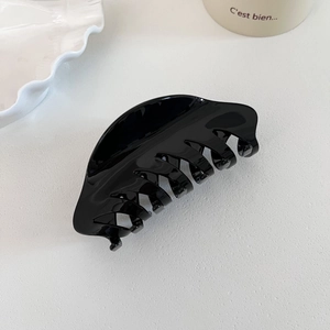 Detail view of a large high-gloss black claw clip made of premium acetate for hair