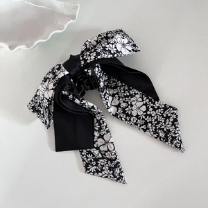 Detail of elegant bow hair claw clip with black floral pattern and satin ribbon design
