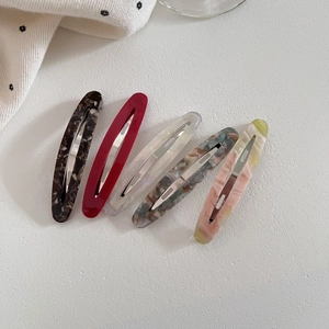 Five hollow oval acetate hair clips in various marble patterns on white background
