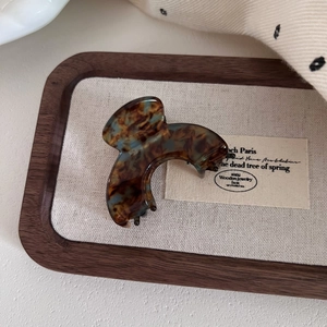 Detailed macro view of an arched tortoiseshell acetate hair claw on a wooden tray