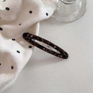 Close-up of tortoise shell acetate oval hair clip with elegant brown and white texture