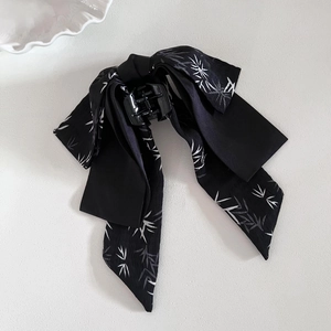 Close-up of black satin bow hair claw clip with elegant bamboo leaf pattern print