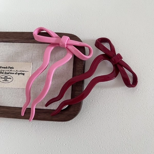 Détail d'épingles à cheveux en acétate rose et bordeaux avec nœud et design en forme de U