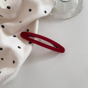 Minimalist red acetate oval hollow hair clip on a stylish white textured surface