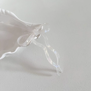 Gros plan sur l'épingle à cheveux en acétate blanc nacré avec nœud et design ondulé en U
