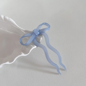 Gros plan d'une épingle à cheveux nœud bleu clair en acétate sur un bol en céramique