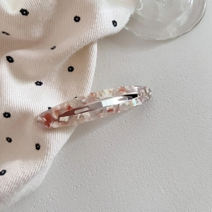 Macro shot of oval acetate hair clip with red and white marble texture and metal base