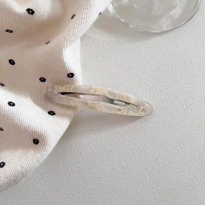 Detailed macro view of hollow oval acetate hair clip with marble texture and metal spring