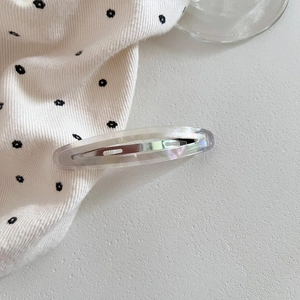 Detail view of oval acetate hair clip with semi-transparent resin and silver metal spring