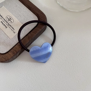 Elegant blue marble heart acetate hair tie with gold label on minimalist wood tray