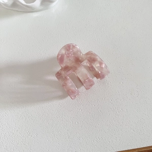 Pince à cheveux carrée en acétate marbré rose sur fond blanc au style minimaliste