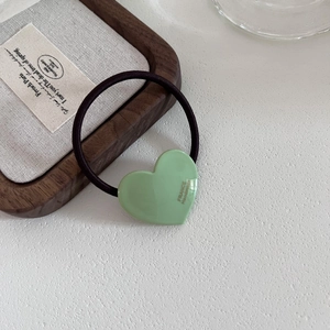 Close-up of a light green acetate heart hair tie with France Handmade text engraving