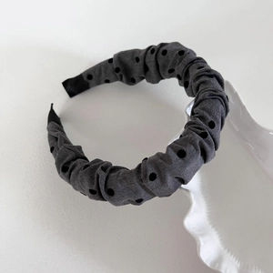 Detail of grey pleated headband with black polka dots and high-top design texture