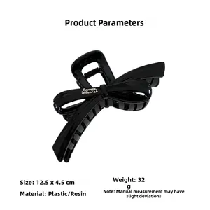 Detail view of large glossy black bow hair claw clip showing 12.5cm size and metal spring