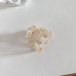 Détail de la pince à cheveux géométrique en acétate crème montrant la forme rectangulaire