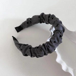 Detail of grey pleated headband with black heart patterns on a white porcelain dish