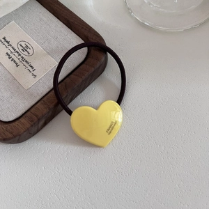 Detailed close-up of yellow acetate heart hair tie with France handmade gold engraving