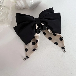 Close-up of black and white polka dot bow hair clip with decorative beads