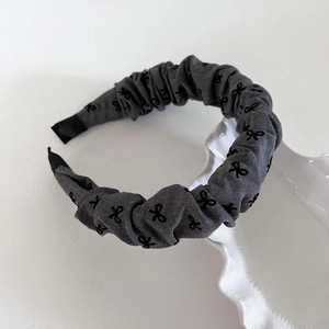 Elegant grey pleated headband with black bow patterns and a stylish puffy design