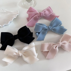 Flat lay of colorful bow hair clips with ruffled edges in pink, blue, black, and white