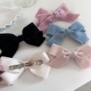 Set of five colorful bow hair clips with ruffled edges on white background