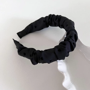 Close-up of black pleated headband with heart pattern on a white ceramic plate