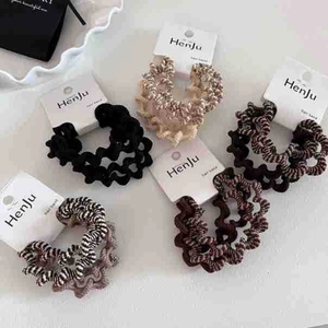 Close-up of wavy spiral hair ties in coffee, black, and cream with zebra pattern