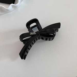Detail of large black glossy bow hair claw clip with Barrette La France text and French style