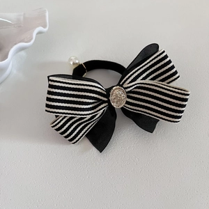 Vue détaillée du chouchou nœud rayé noir et blanc avec bouton doré et perle blanche