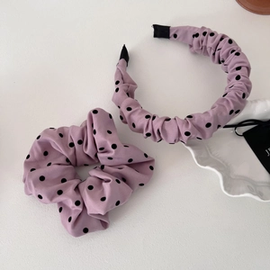 Ensemble serre-tête violet à pois et chouchou assorti sur une plaque blanche décorative