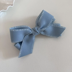 Macro detail of Morandi blue bow hair clip with ruffled edges and textured fabric