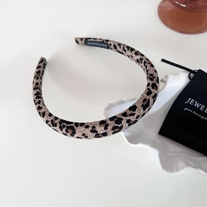 Detail of leopard print headband featuring a black handmade woven label and fabric texture