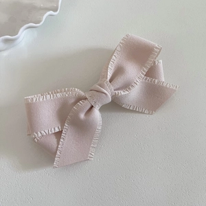 Detail of a dusty rose pink bow hair clip with elegant ruffled edges and fabric texture