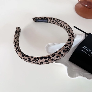Elegant leopard print fabric headband placed on a white ceramic tray in a cozy setting