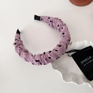 Détail d'un serre-tête plissé lavande avec des motifs de petits cœurs noirs imprimés