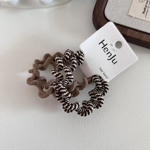 Detail of khaki and zebra print wavy elastic hair bands on a white minimalist background