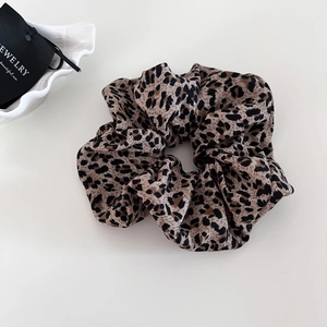 Detail of oversized leopard print scrunchie with soft fabric texture and pleated design