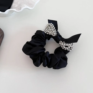 Elegant black satin scrunchie with silver bead bow tie decoration on white background