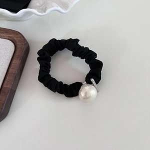 Close-up of black pleated fabric hair tie featuring a large elegant white pearl detail