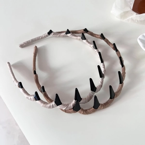 Macro detail of beige and brown fabric wrapped wavy headbands with black punk spikes