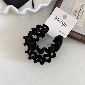 Detail shot of a black wavy texture hair band on a minimalist display tray