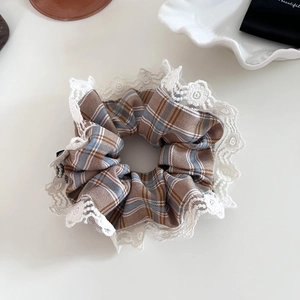 Detail of blue and brown plaid scrunchie with delicate white lace embroidery edges