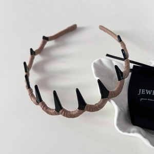 Close-up of wavy fabric headband with black spiked design and brown woven texture