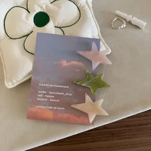 Lot de 3 barrettes étoiles en acétate rose vert et beige sur un fond floral élégant