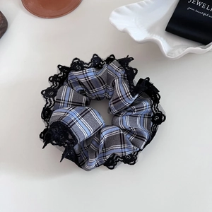 Detail of blue plaid scrunchie with black lace trim next to a jewelry pouch
