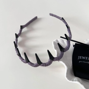 Close-up of deep purple fabric headband featuring black metallic punk cone spikes